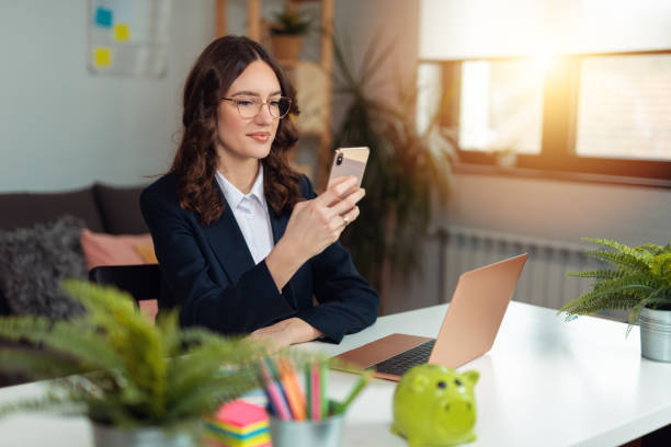 Business woman working from home. Business woman using phone at home for work stock photo