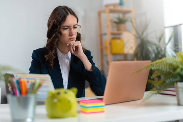 Confused business woman examining documents at desk stock photo