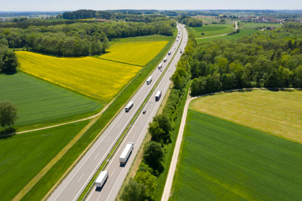 Highway with Trucks in Rural Area, Aerial View Multiple lane highway with car and truck traffic, bird's eye view. autobahn stock pictures, royalty-free photos & images