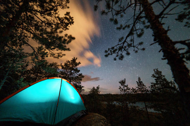 istock Night scene with illuminated camping tent, forest, starry sky and illuminated clouds 1400304423