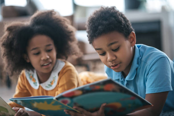 istock Two kids lying on the floor and reading a book 1400305313