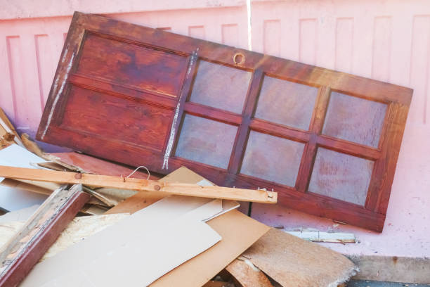 an old interior wooden door with frosted glass thrown into the trash, illuminated by the rays of the sun on the right