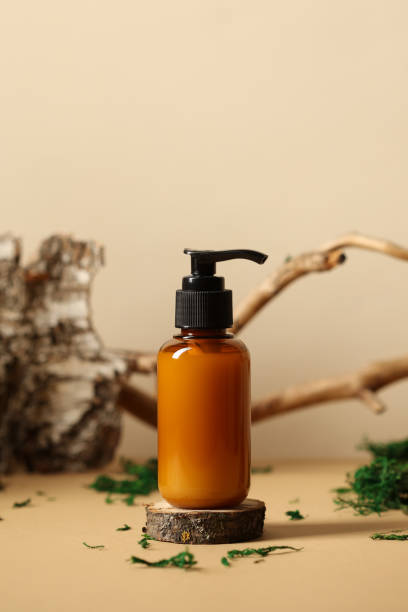 istock Amber glass pump dispenser bottle mockup. SPA natural organic cosmetics packaging design. Tree branch, birch bark and moss on background. 1400306498