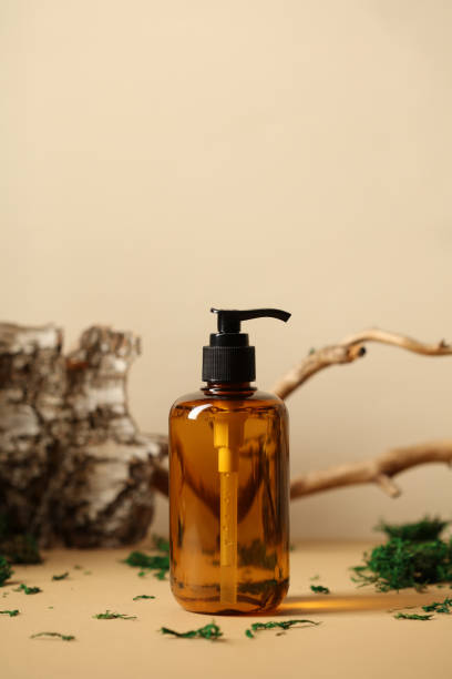 istock Amber glass pump shampoo bottle mockup. SPA natural organic cosmetics packaging design. Tree branch, birch bark and moss on background. 1400306504