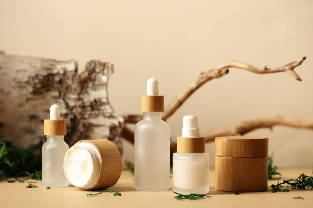 SPA natural organic cosmetics packaging design. Set of transparent glass bottles, moisturizer cream in wooden jars. Tree branch, birch bark and moss on background. stock photo
