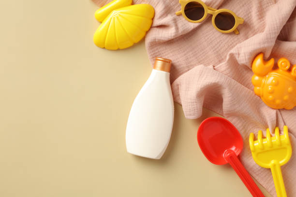 istock Flat lay composition with baby sunscreen lotion, sunglasses, sand molds, towel on beige background. Sun protection for babies concept. 1400307578