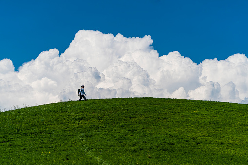 yeşil çayır tepe, beyaz bulutlar, mavi gökyüzü ve sanal gerçeklik gözlüğü takmış adam. yeşil renk, mavi renk ve beyaz renk uyumu full frame makine ile çekilmiştir.