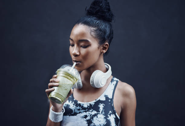 istock One active young mixed race woman drinking a healthy green detox smoothie while exercising outdoors. Female athlete sipping on fresh nutritious fruit juice with straw in plastic cup to cleanse, provide energy and vitamins for training 1400312016