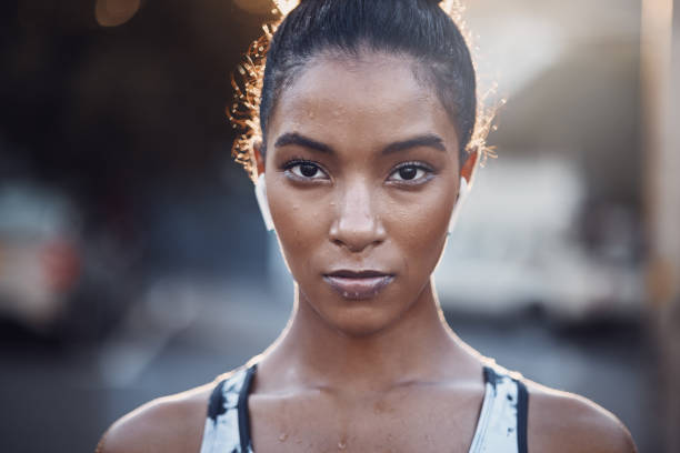 Closeup portrait of one focused mixed race woman sweating after an intense workout or run in the city. Face of determined and motivated female athlete wearing earphones and taking a break from exercise outdoors retrato en primer plano de una mujer de raza mixta enfocada sudando después de un entrenamiento intenso o correr en la ciudad. rostro de atleta femenina decidida y motivada que usa auriculares y se toma un descanso del ejercicio al aire libre