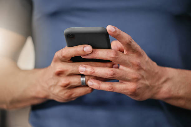 istock Closeup of one active caucasian man texting on cellphone with while on break from exercise in a gym. Male athlete browsing fitness apps, social media and watching workout tutorials online 1400313540