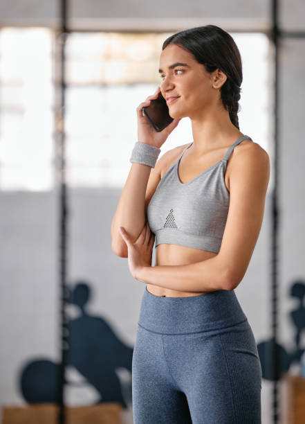 istock One active young hispanic woman talking on a cellphone while taking a break from exercise in a gym. Happy female athlete chatting on phone after her workout in a fitness centre 1400313545