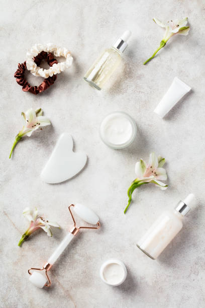 istock Face massage roller, gua sha, serum, female accessories on stone table. Anti aging cosmetics set. Flat lay, top view 1400313568