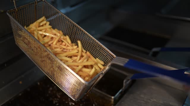 Woman preparing french fries at a commercial kitchen