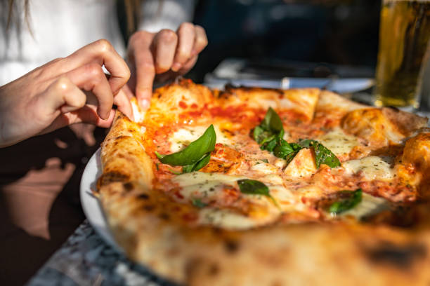 donna irriconoscibile che prende una fetta di pizza - pizzeria foto e immagini stock