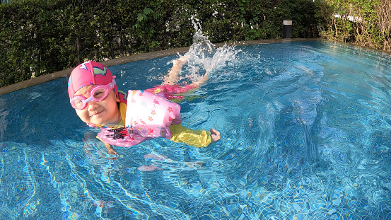 Asian girl in a swimsuit swims in the pool.