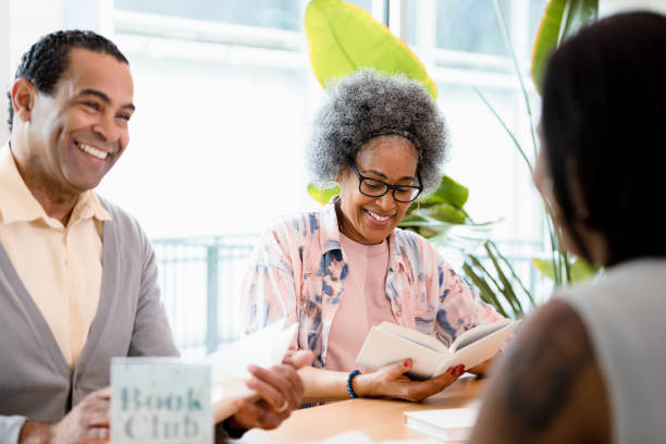 istock Mature couple smiles while discussing book with friends 1400319334