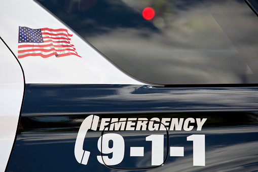 Police cruiser with American flag decal and Call 911 Emergency number