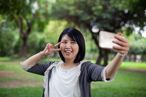 Smiling woman taking selfie with phone at park, Taipei