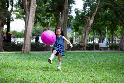 Little Asian girl playing with a soccer ball in park Taipei