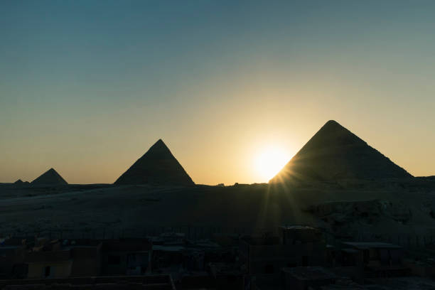 valle con le grandi piramidi nella luce notturna al tramonto. il sole tramonta dietro la piramide. foto panoramica dal tetto del cairo. piramidi egiziane con tramonto - sphinx night pyramid cairo foto e immagini stock