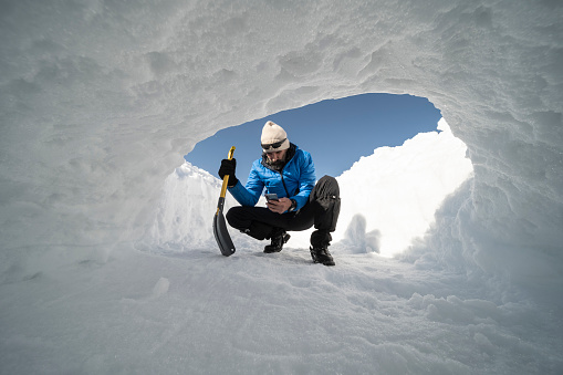 Snow shelter. Winter adventures and survival in the snow. Man snowshoeing and spending vacation in nature.