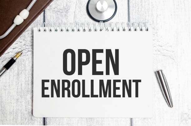 istock Top view of stethoscope and text Open Enrollment on notebook on wooden background 1400339375