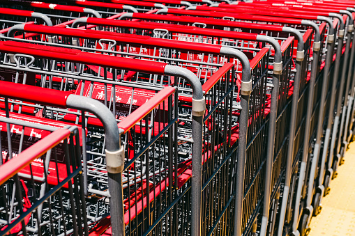 Close-up of metal supermarket carts with red handles on the street