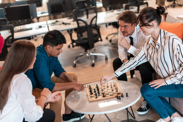 istock Multiethnic group of business people playing chess while having a break in relaxation area at modern startup office 1400345076