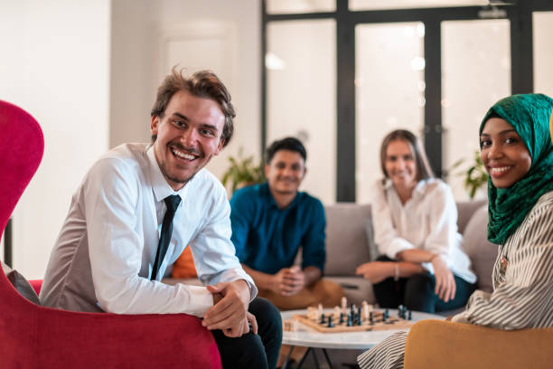 Multiethnic group of business people playing chess while having a break in relaxation area at modern startup office.