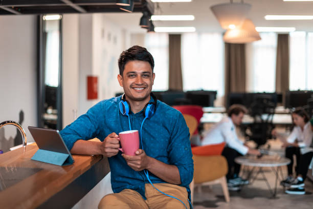 istock Casual business man taking break from the work using laptop while drinking tea in relaxation area of modern open plan startup office 1400345185