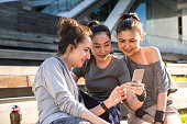 istock Young ladies sitting on the roadside using a smartphone - stock photo 1400349914