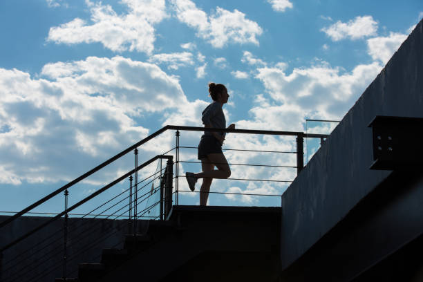 a young woman exercising on an urban building on a sunny summer day. silhouette. - stock photo - hair bun asian ethnicity profile women imagens e fotografias de stock