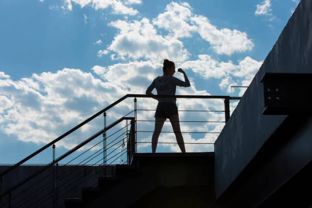 una joven haciendo ejercicio en un edificio urbano en un soleado día de verano. silueta. - foto de archivo - hair bun asian ethnicity profile women fotografías e imágenes de stock