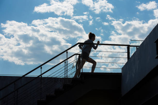 una joven haciendo ejercicio en un edificio urbano en un soleado día de verano. silueta. - foto de archivo - hair bun asian ethnicity profile women fotografías e imágenes de stock