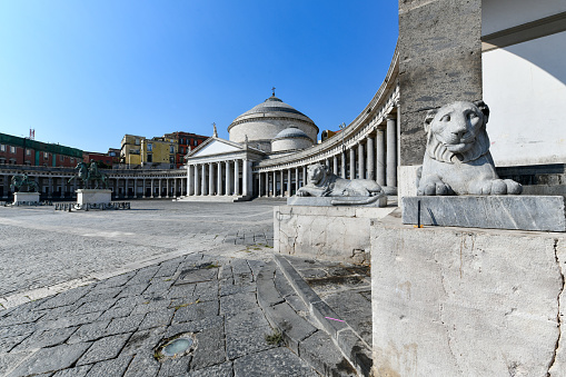 View of Basilica Reale Pontificia San Francesco da Paola church on Piazza del Plebiscito, main square of the city, and stone lion sculptures in Naples, Italy.