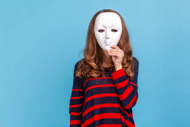istock Anonymous woman standing hiding face behind white mask, conspiracy and privacy, secrets. 1400353677