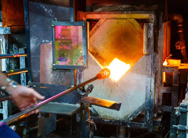 Softening glass in a kiln during glassblowing process