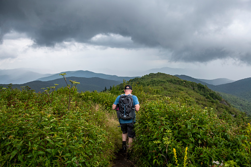 A man hikes in rain on the approximately five-mile-long Black Balsam Knob and Tennent Mountain Loop trail in Pisgah National Forest southwest of Asheville, North Carolina. The trail is accessed from the Blue Ridge Parkway. Photo taken on Tennent Mountain.