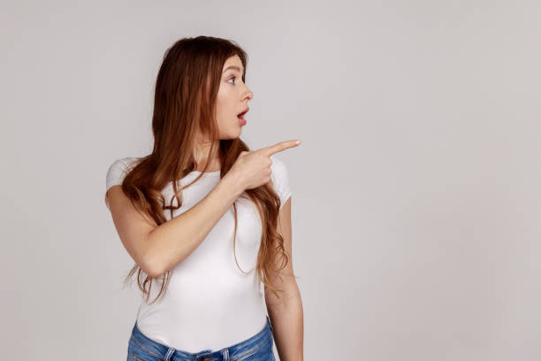 istock Woman pointing empty space, showing blank wall for commercial idea, looking away. 1400354833