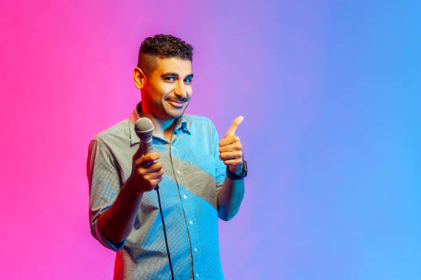 istock Man posing with microphone in hands, offers mic, journalist asking questions, showing thumb up. 1400355672