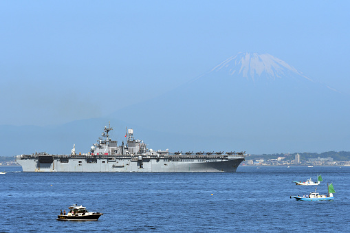 Kanagawa, Japan - May 29, 2022: United States Navy USS Tripoli (LHA-7), America-class amphibious assault ship sailing in Tokyo Bay with Mt. Fuji in the background.