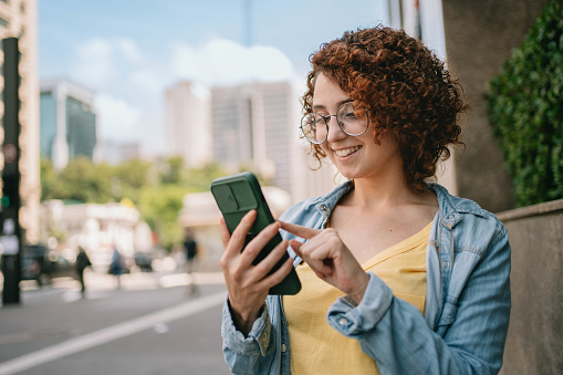 University student using smart phone at Paulista Avenue in Sao Paulo , Brazil