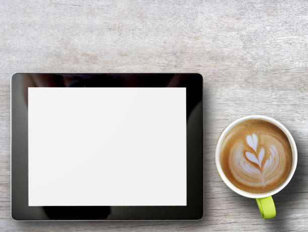 istock Tablet and cup of coffee on wood table background. 1400363352
