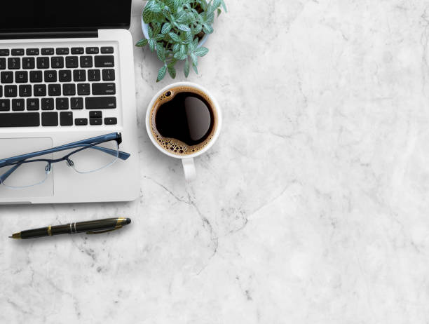 istock Top view blank notebook,glasses,pen,cup of coffee on white marble background. 1400363456