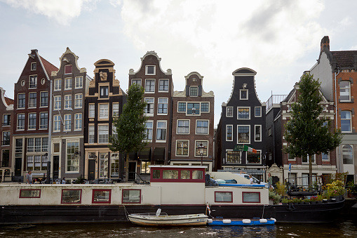 Narrow crooked waterfront canal houses at Amstel River, Amsterdam, The Netherlands.