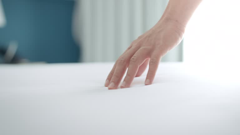 Close up hand of woman dragging on clean white bed gently with relax, Slow motion