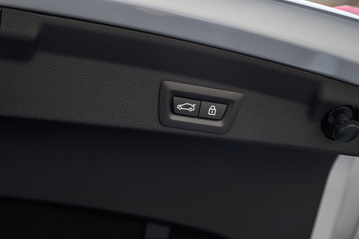 Closeup of power liftgate/trunk close and lock buttons on a silver car.