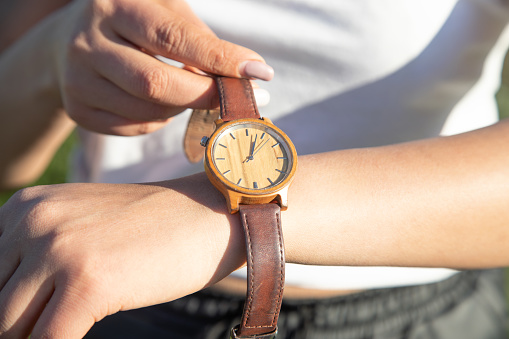 Caucasian girl with a wristwatch in hand.