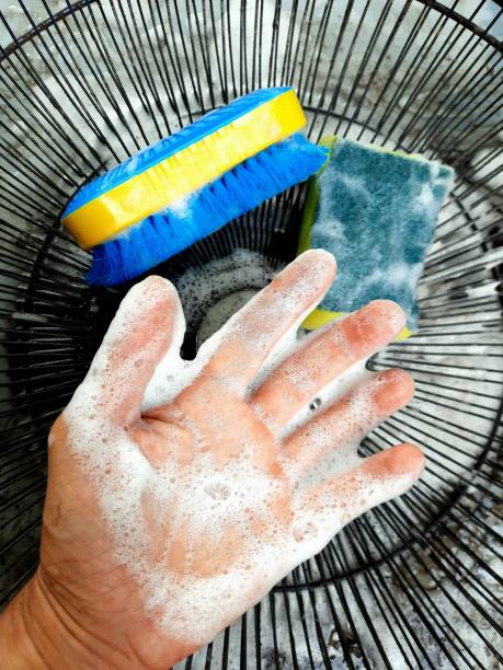 Detergent foam on hand cleaning electric fan part.