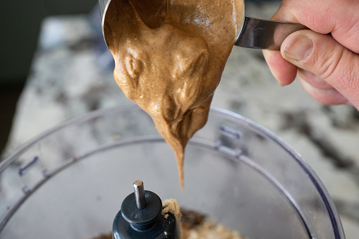 Peanut butter falling into blender from measuring cup